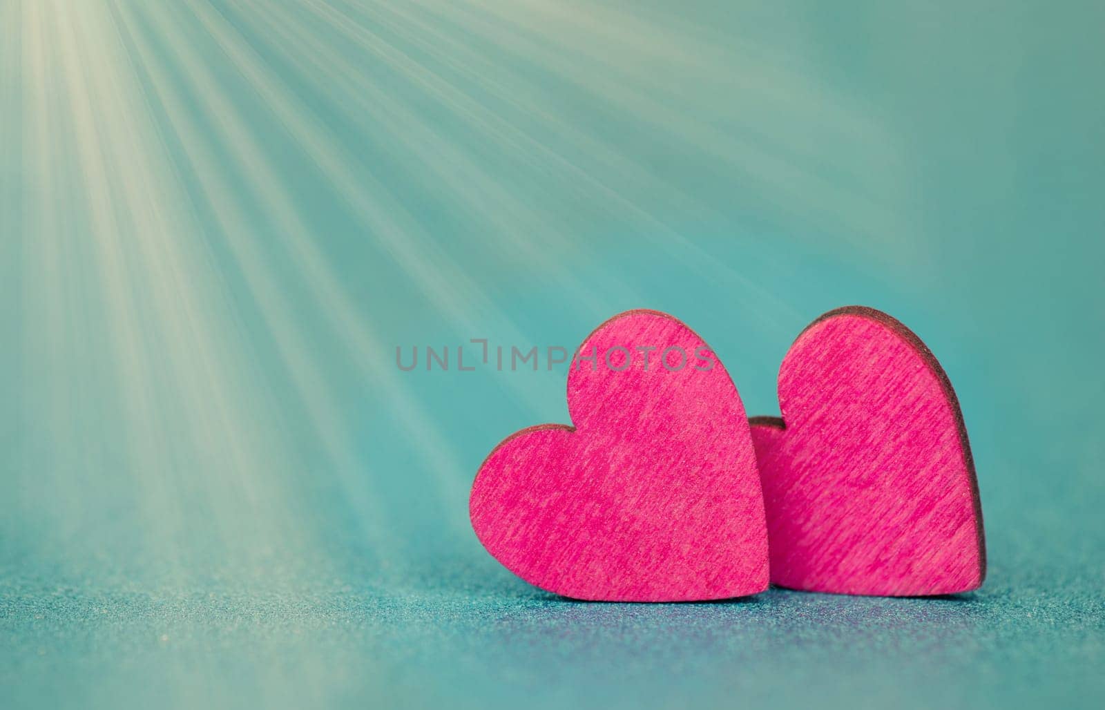 Pink hearts on a turqouise background with sunbeams, valentine greeting card, mothers day and birthday wishes, love symbol