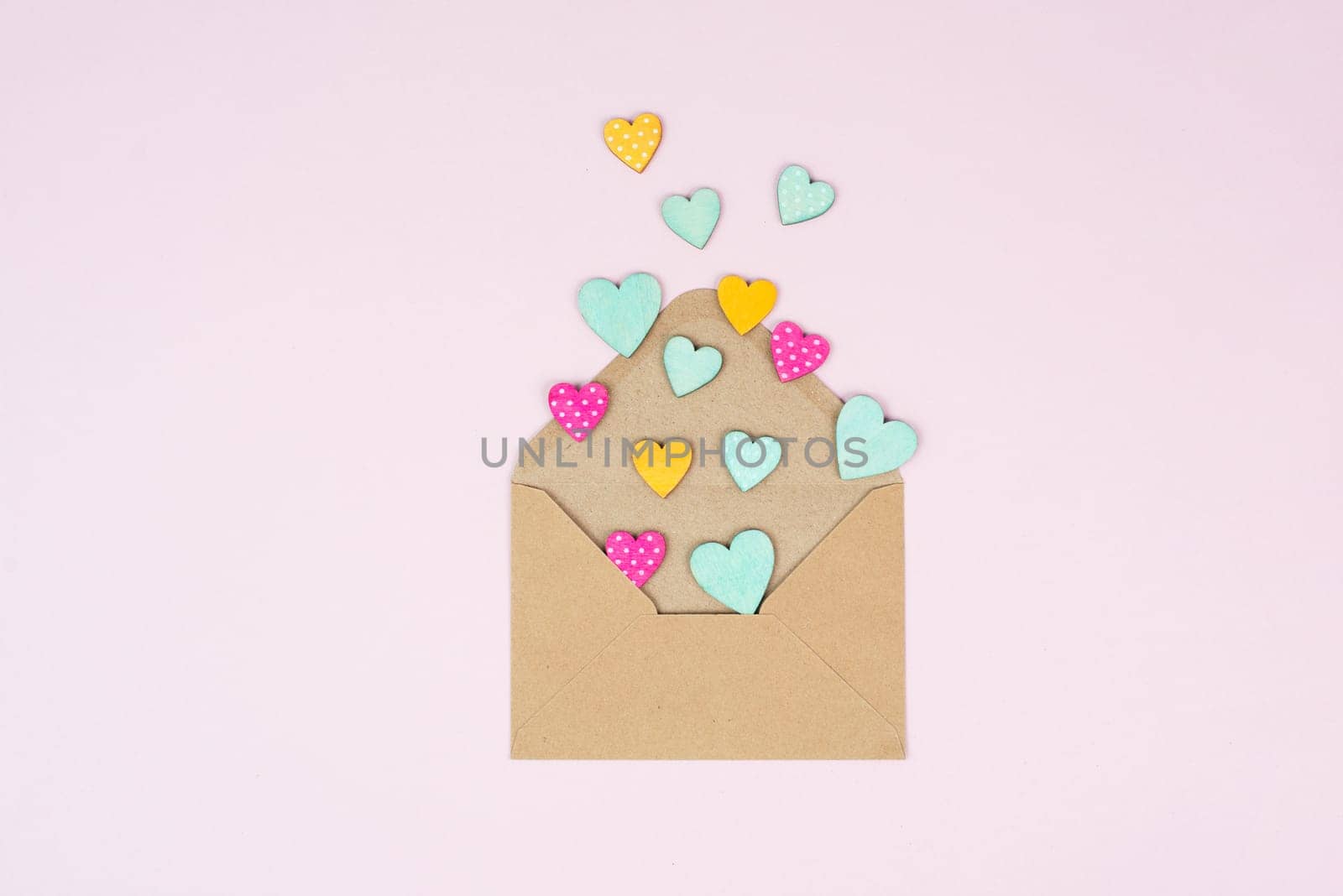 Valentine day greeting card, envelope with hearts on pastel background, love symbol, flat lay