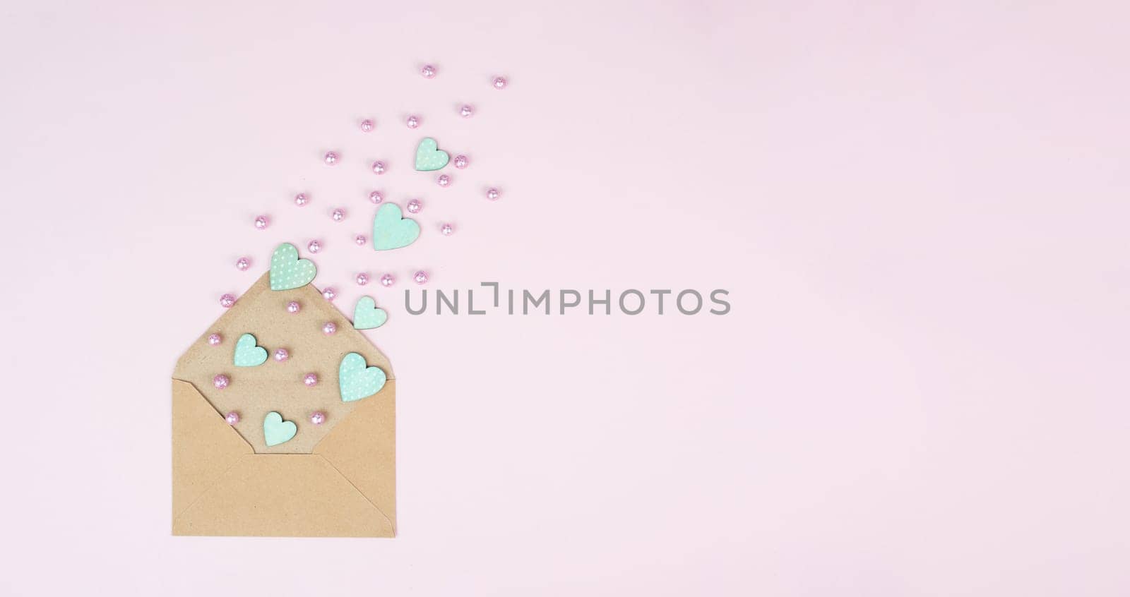 Valentine day greeting card, envelope with hearts on pastel background, love symbol, flat lay