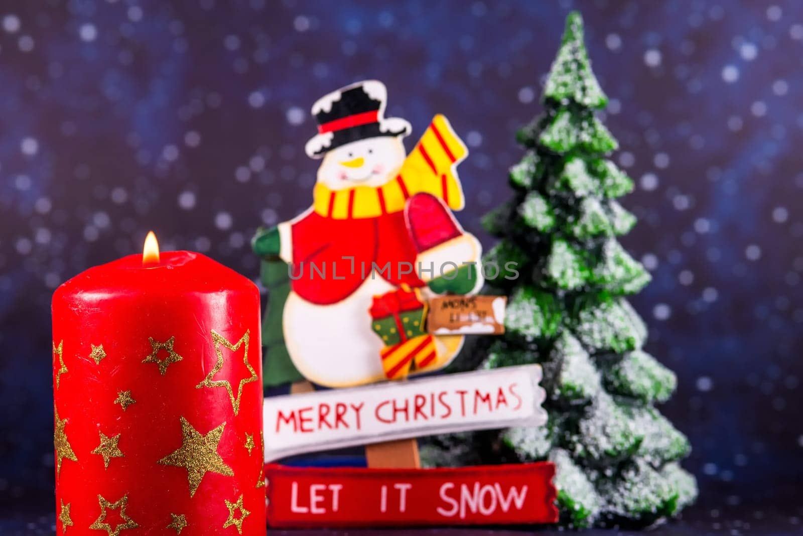 burning candle with Santa Claus and snowy fir tree in the background