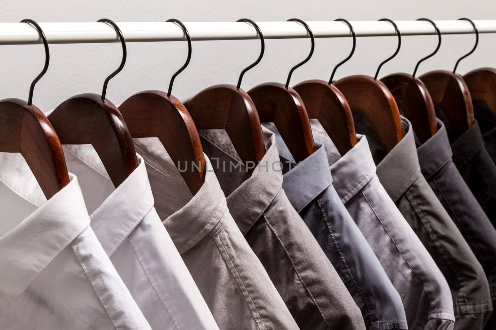 Several shirts on a hanger. from white to black color range.