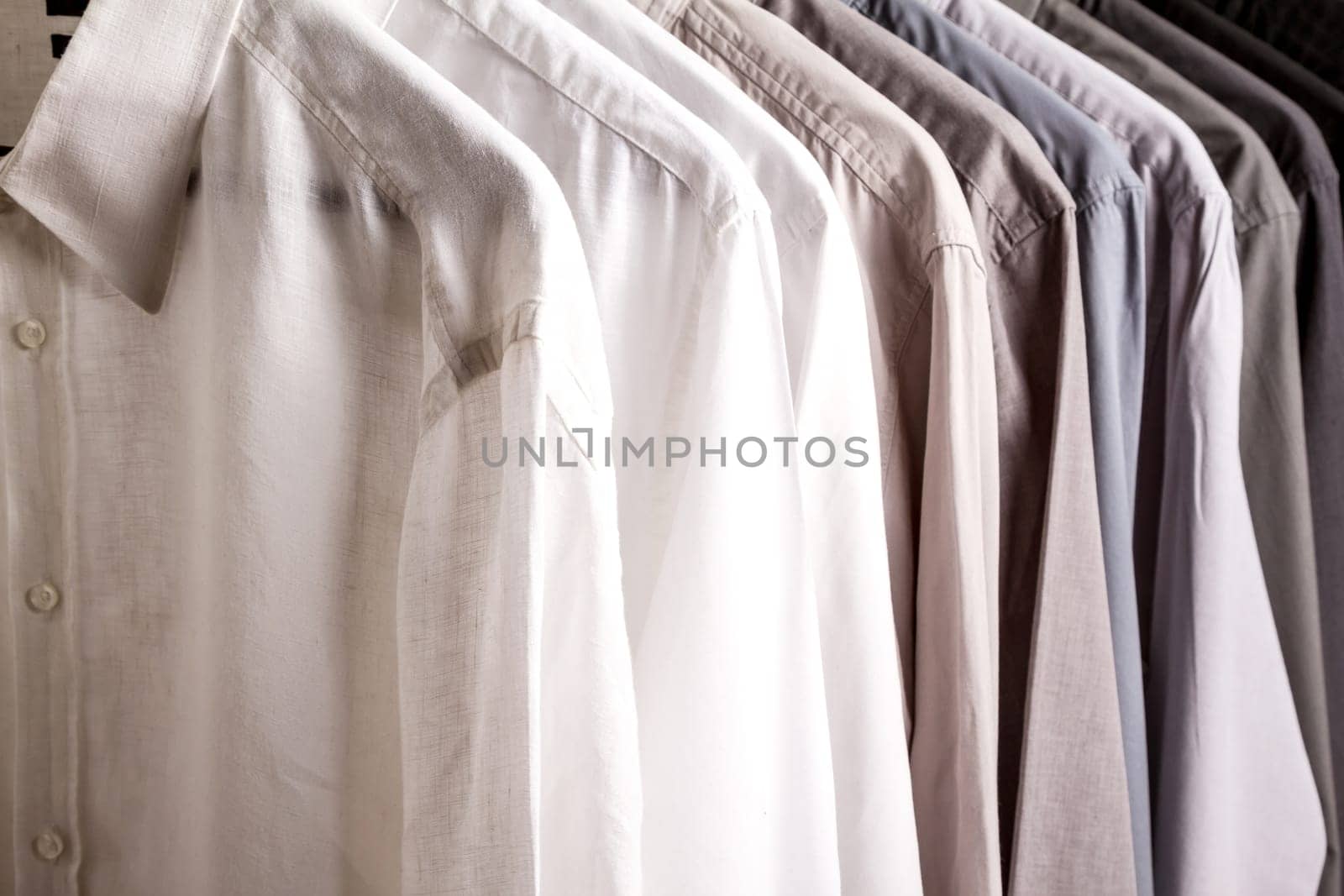 Several shirts on a hanger. from white to black color range.