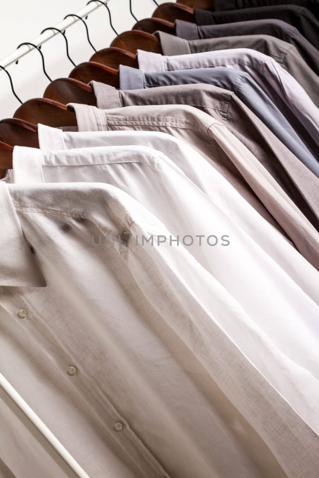 Several shirts on a hanger. from white to black color range.
