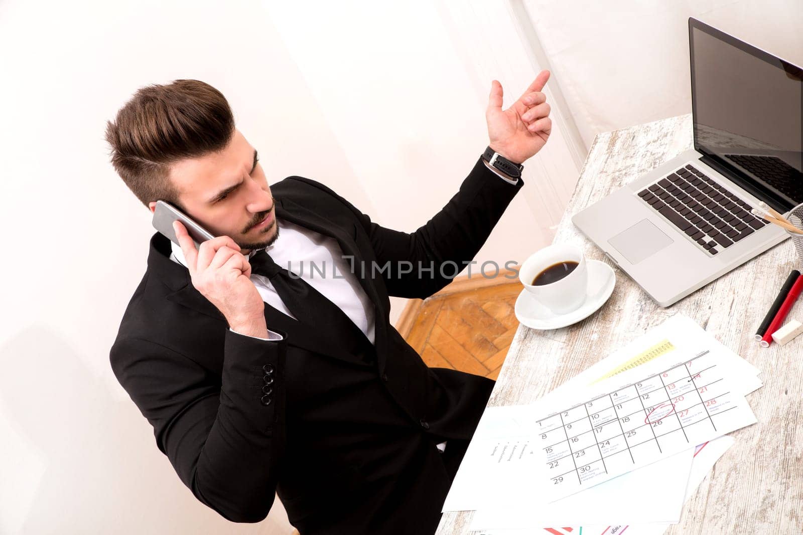 Businessman checking appointments in the calendar at the office and talking by phone.