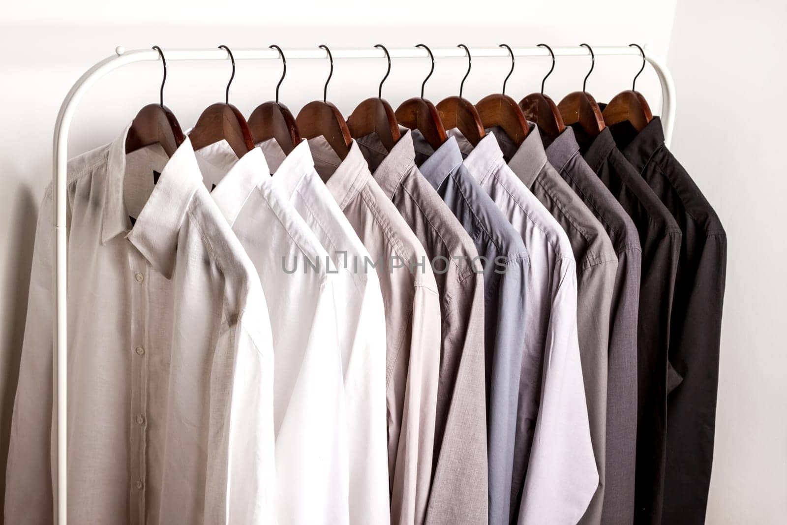 Several shirts on a hanger. from white to black color range.