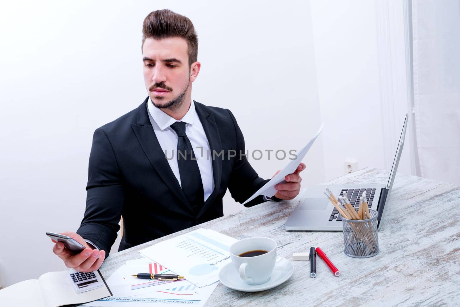 Working at the office with the laptop and some documents.