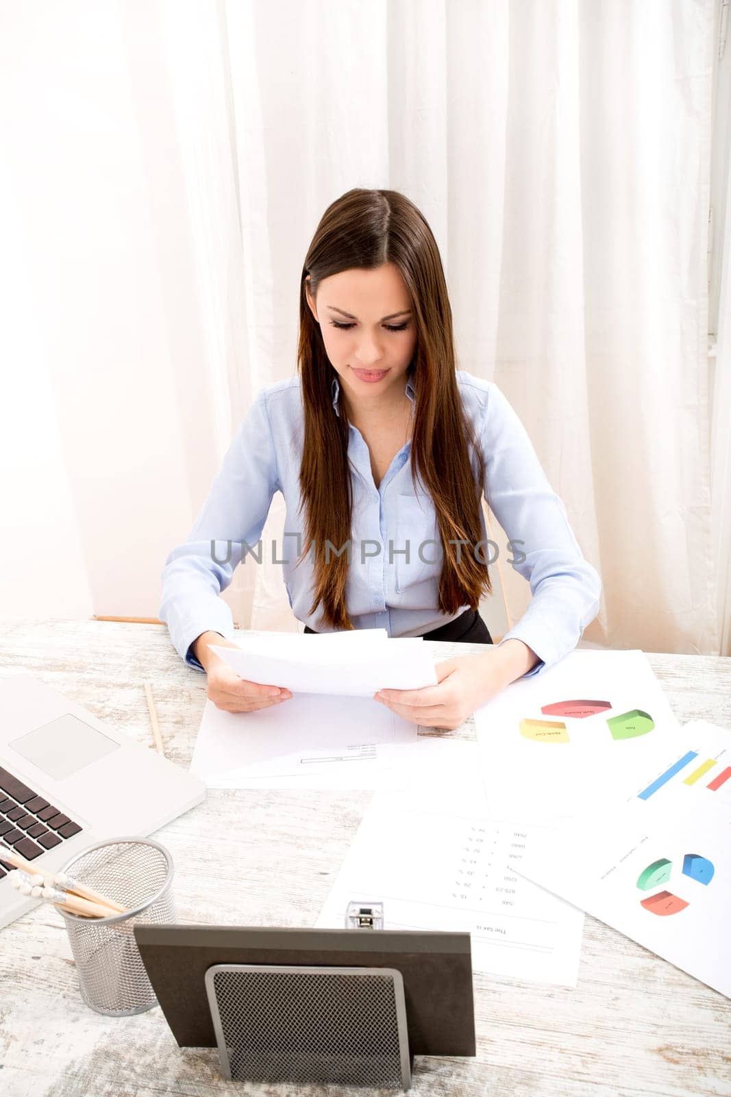 Businesswoman working at the office with the laptop and some documents.