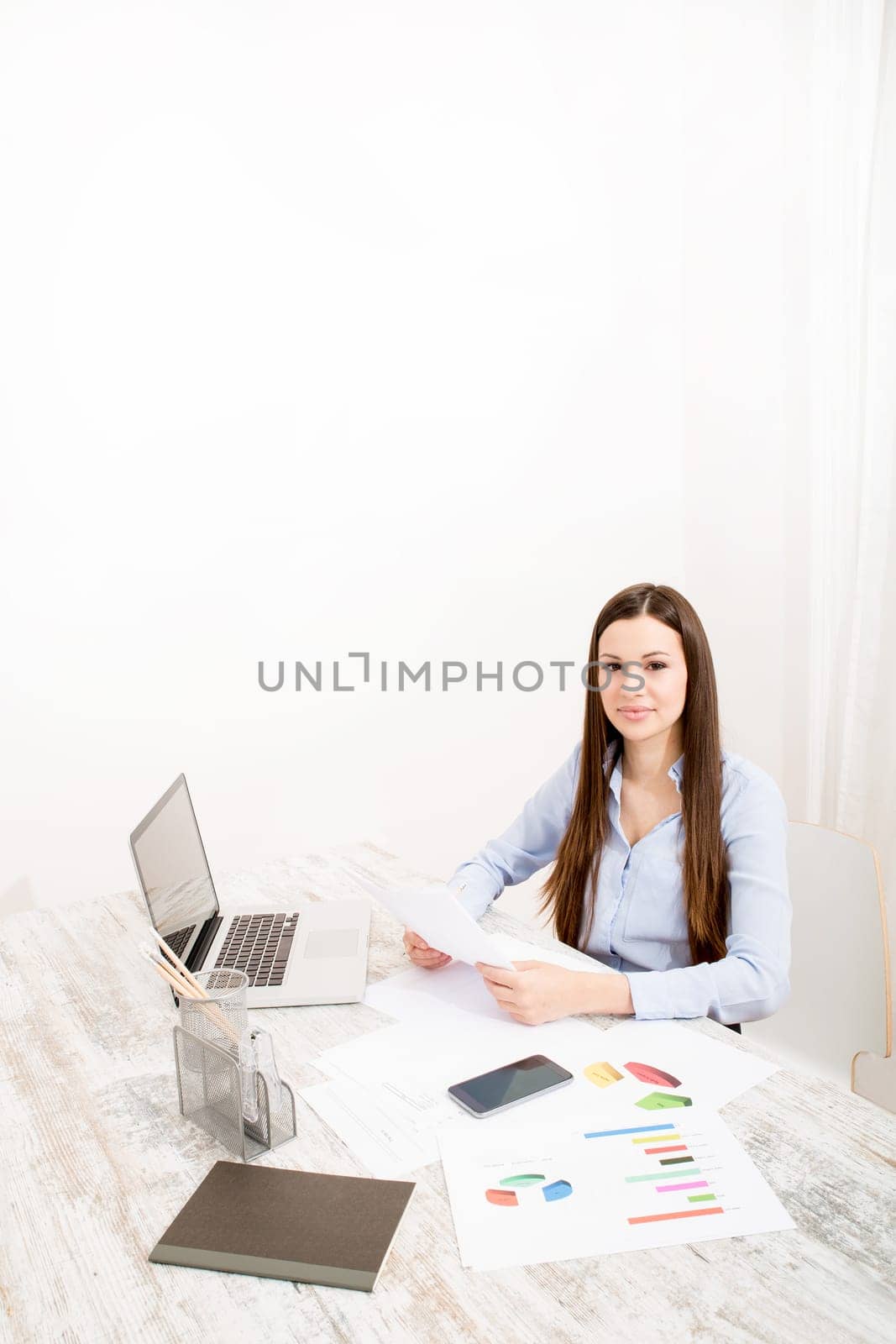 Businesswoman working at the office with the laptop and some documents.