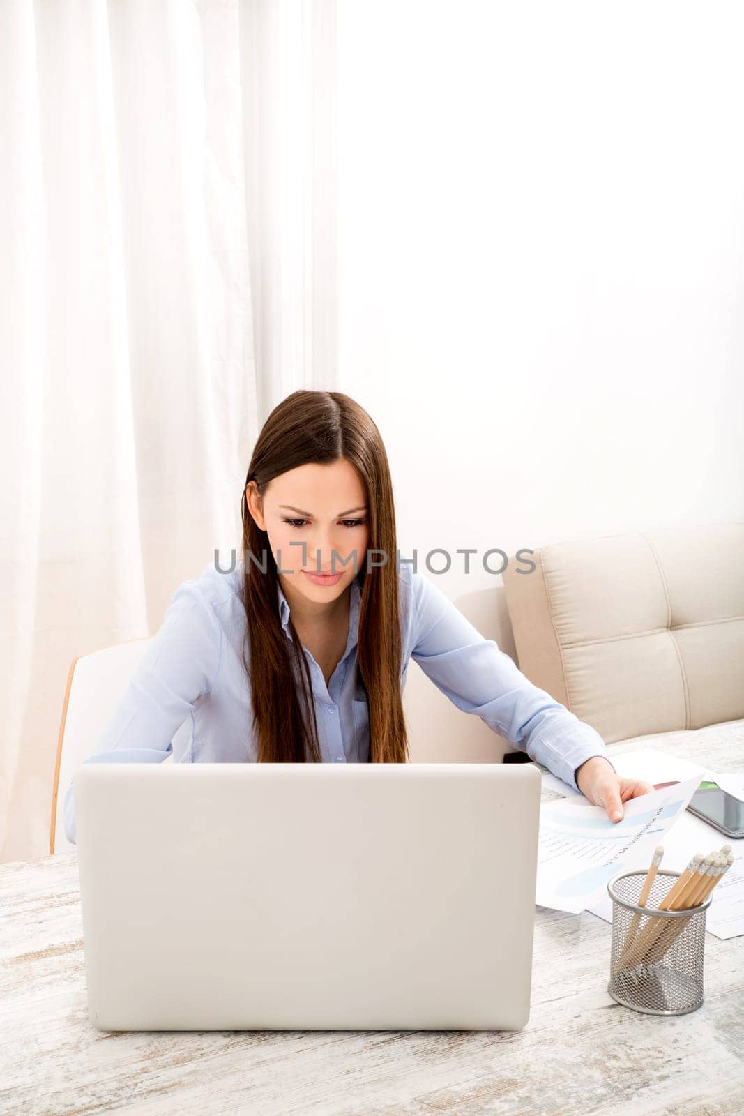 Businesswoman working at the office with the laptop and some documents.