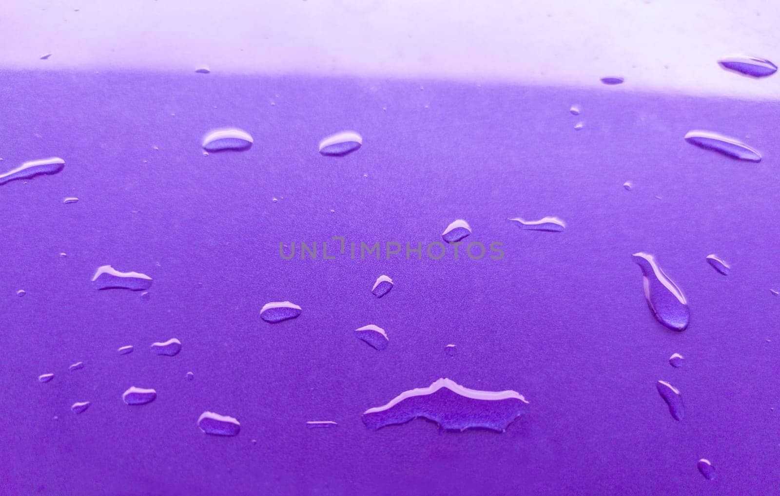 Landscape of drops on the car body after washing it with a pressure gun. Purple color