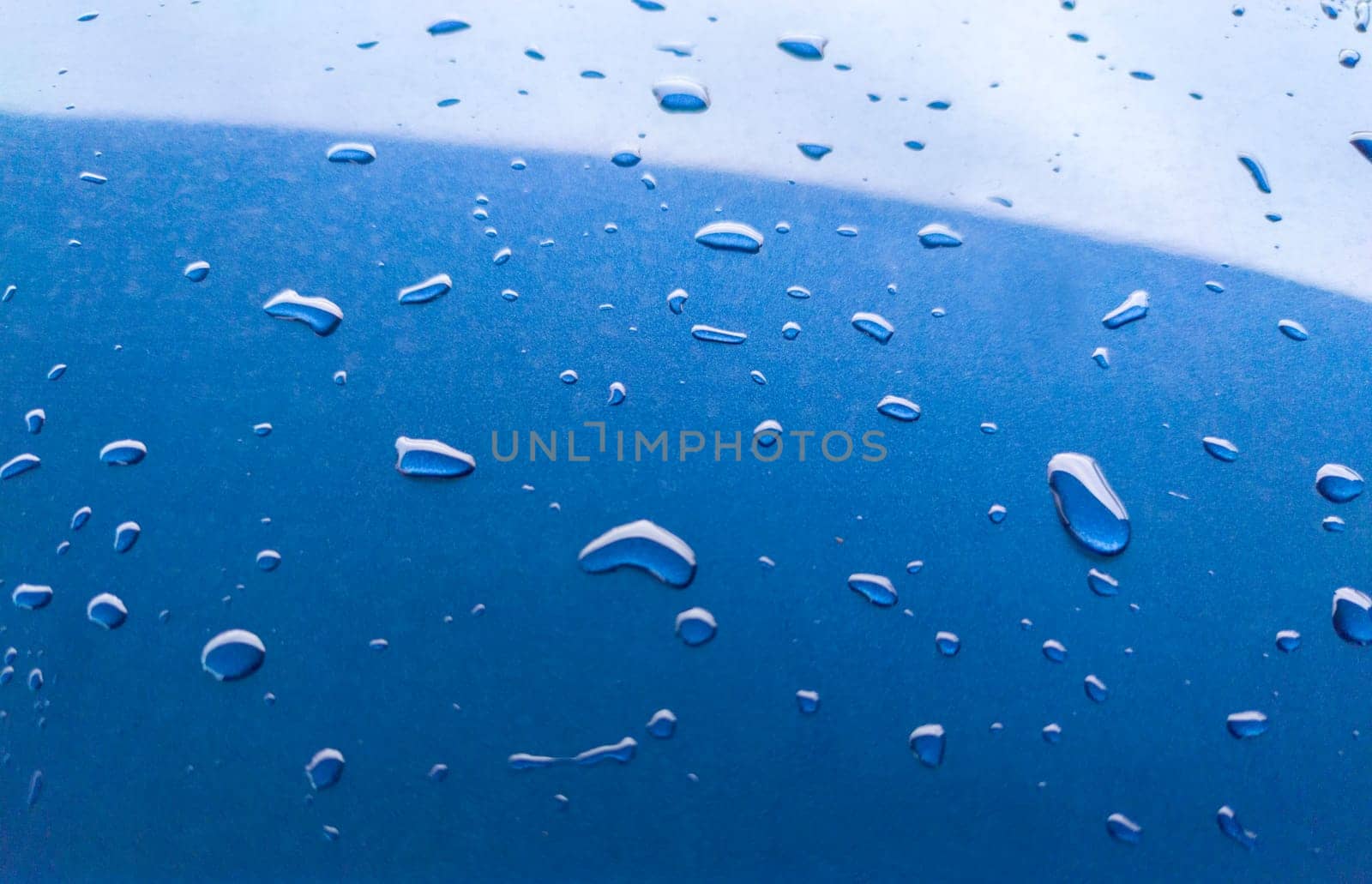 Landscape of drops on the car body after washing it with a pressure gun. Light blue
