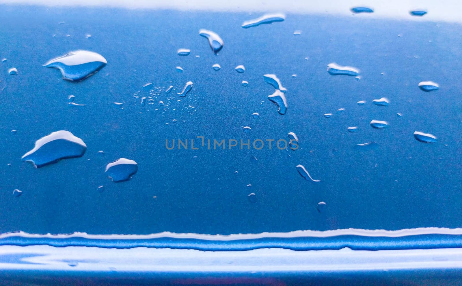 Landscape of drops on the car body after washing it with a pressure gun. Light blue