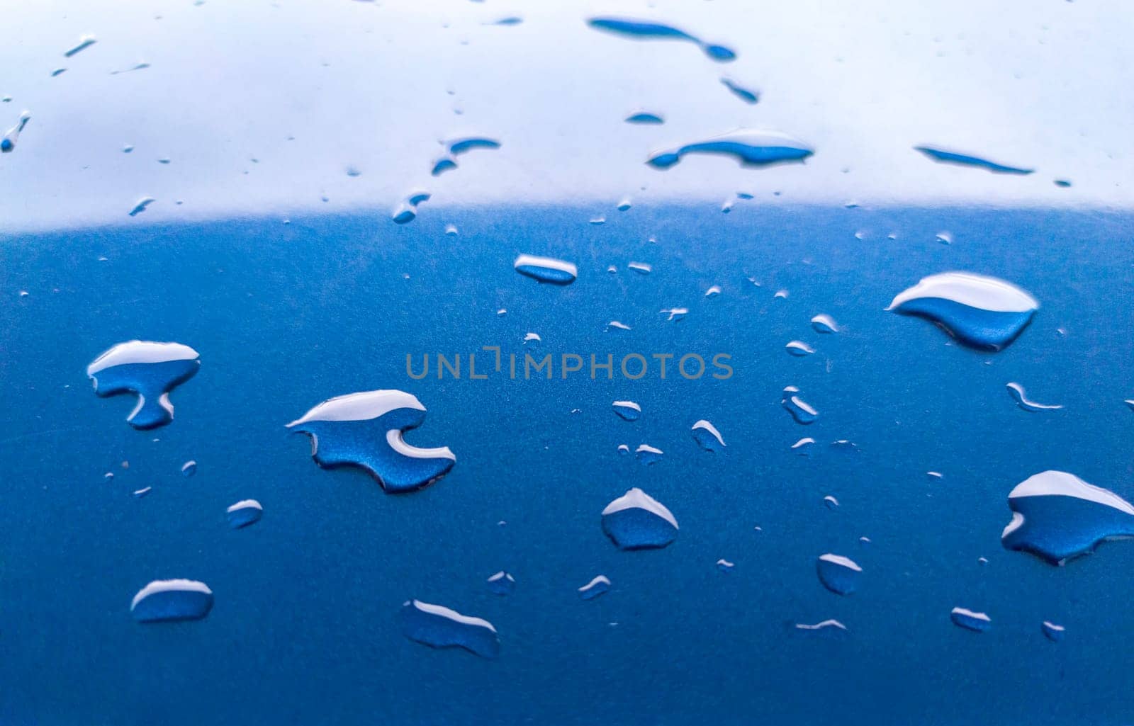 Landscape of drops on the car body after washing it with a pressure gun. Light blue