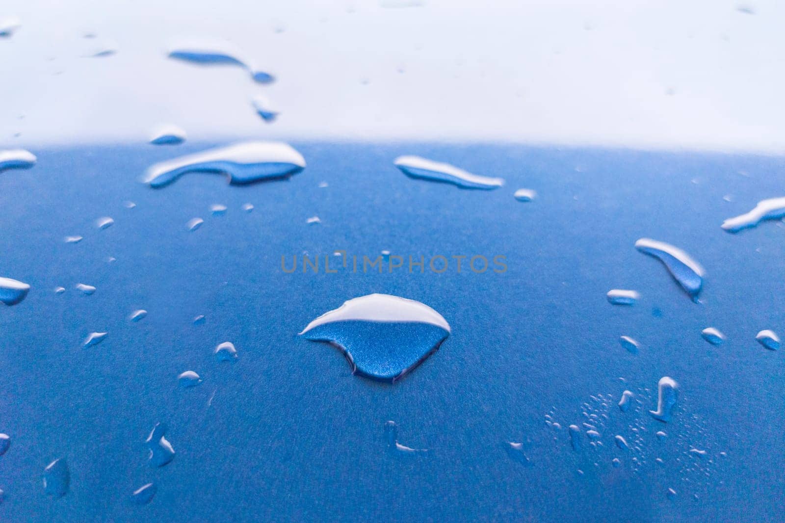 Landscape of drops on the car body after washing it with a pressure gun. Light blue