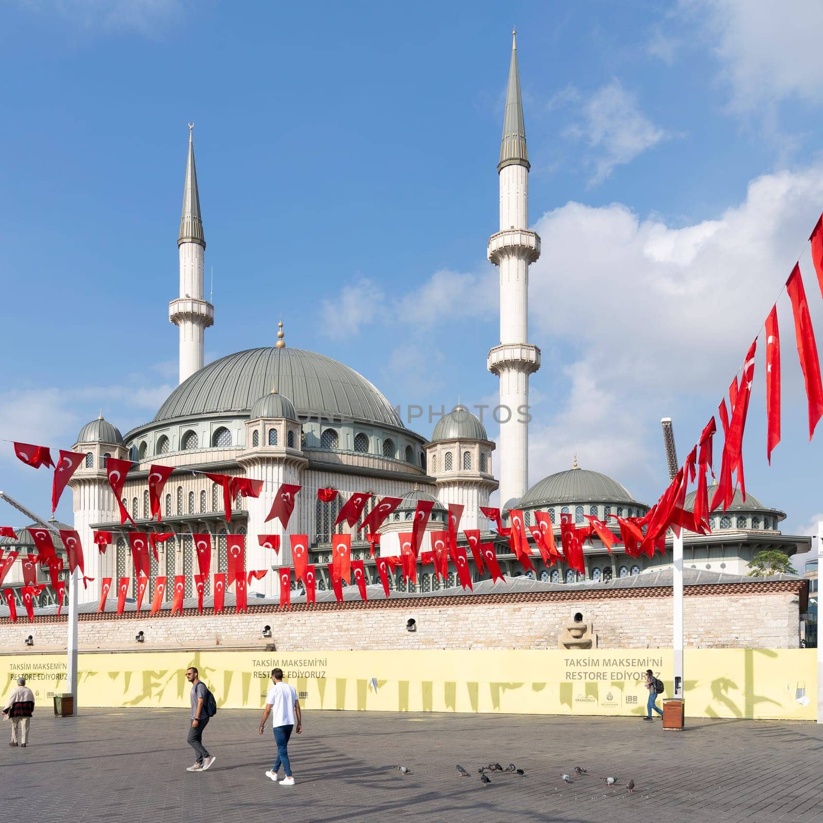Istanbul, Turkey - September 2 2022: Few pedestrians walking in front of Taksim Mosque, in the early morning, at Taksim Square, Beyoglu district, central Istanbul, in a sunny summer day