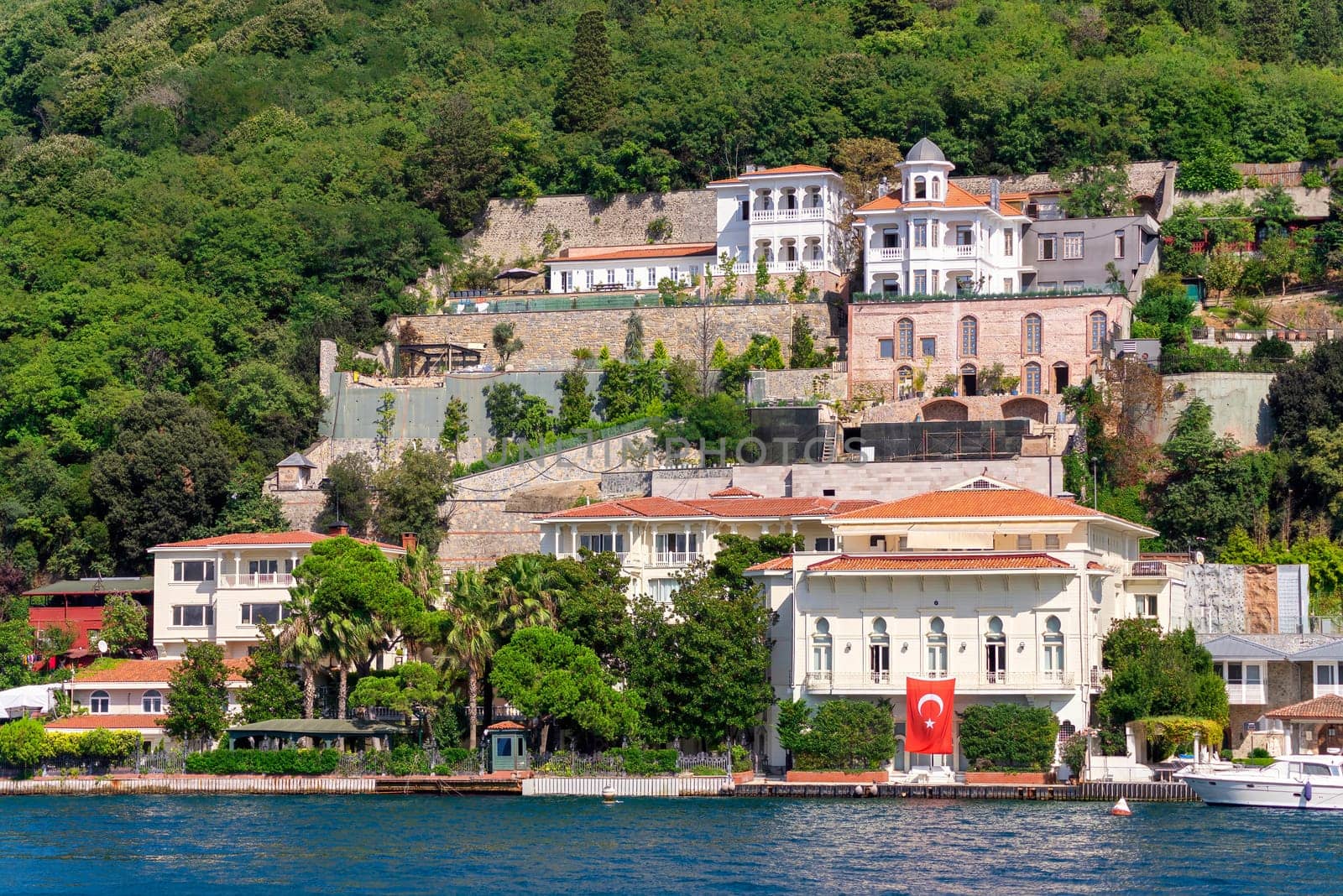 View from Bosphorus strait of the green mountains of the Asian side, with traditional houses and dense trees in a summer day, Istanbul, Turkey