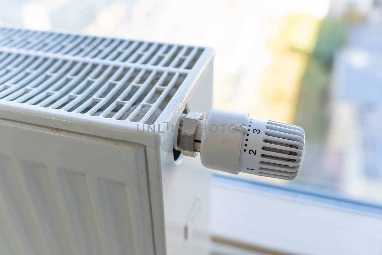 Heating radiator with adjustment knob installed on the middle position in a residential apartment.