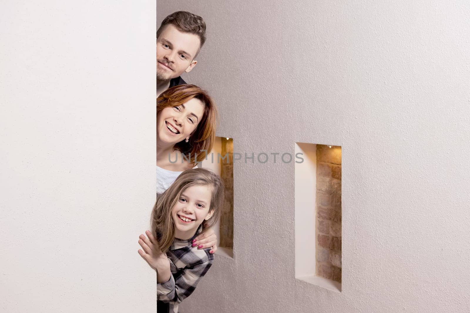 Tricky family peeks around the corner of the wall at home