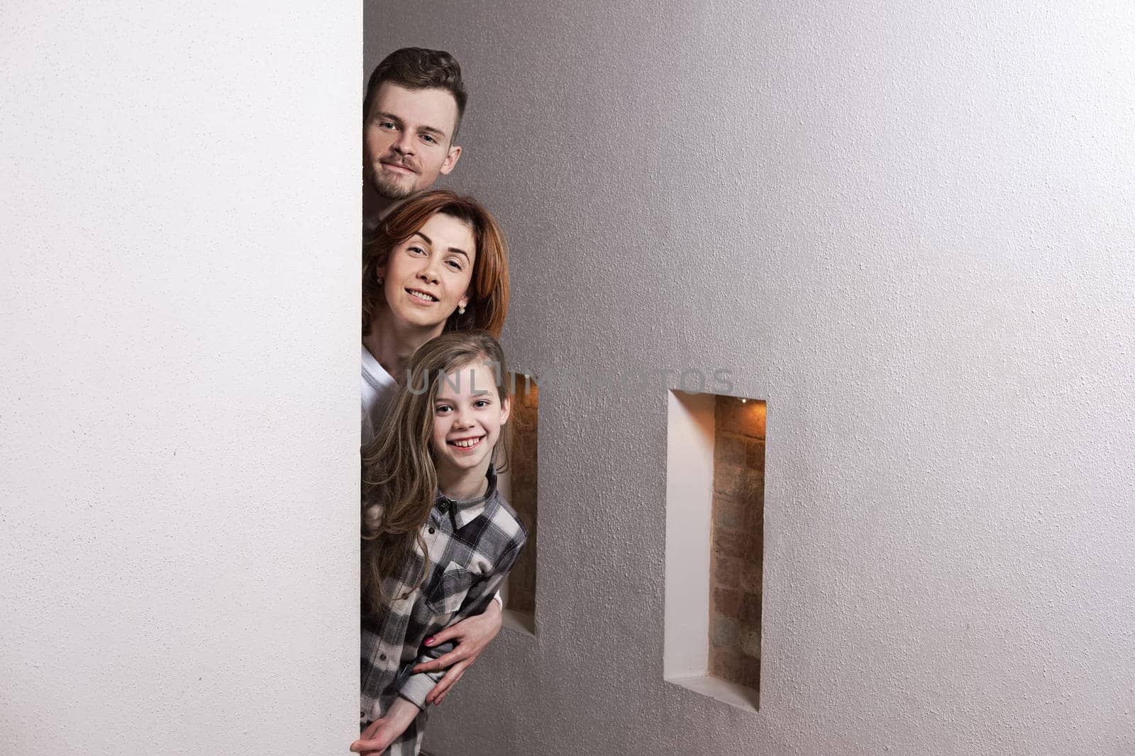 Tricky family peeks around the corner of the wall at home