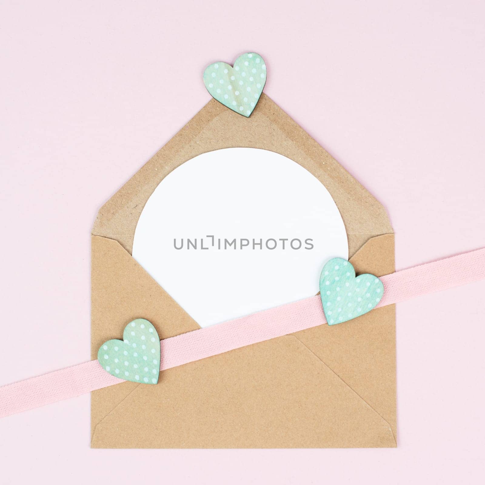 Valentine day greeting card, envelope with hearts on pastel background, love symbol, flat lay