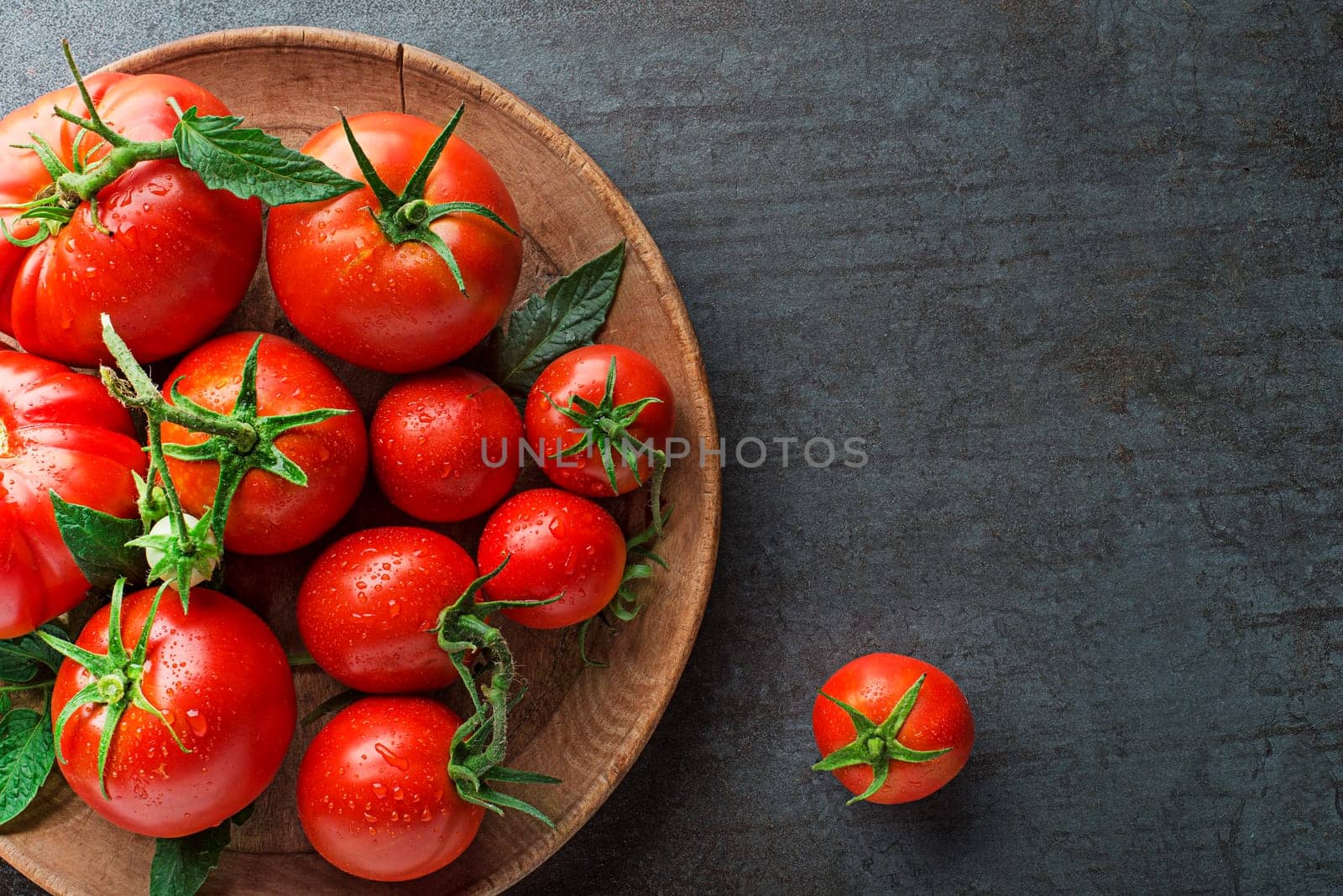 Fresh tomatoes in a plate on a dark background. Harvesting tomatoes. Top view
