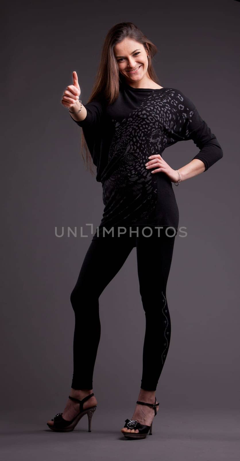 A long-haired beautiful self-confident woman posing in a classical thumbs up all right pose