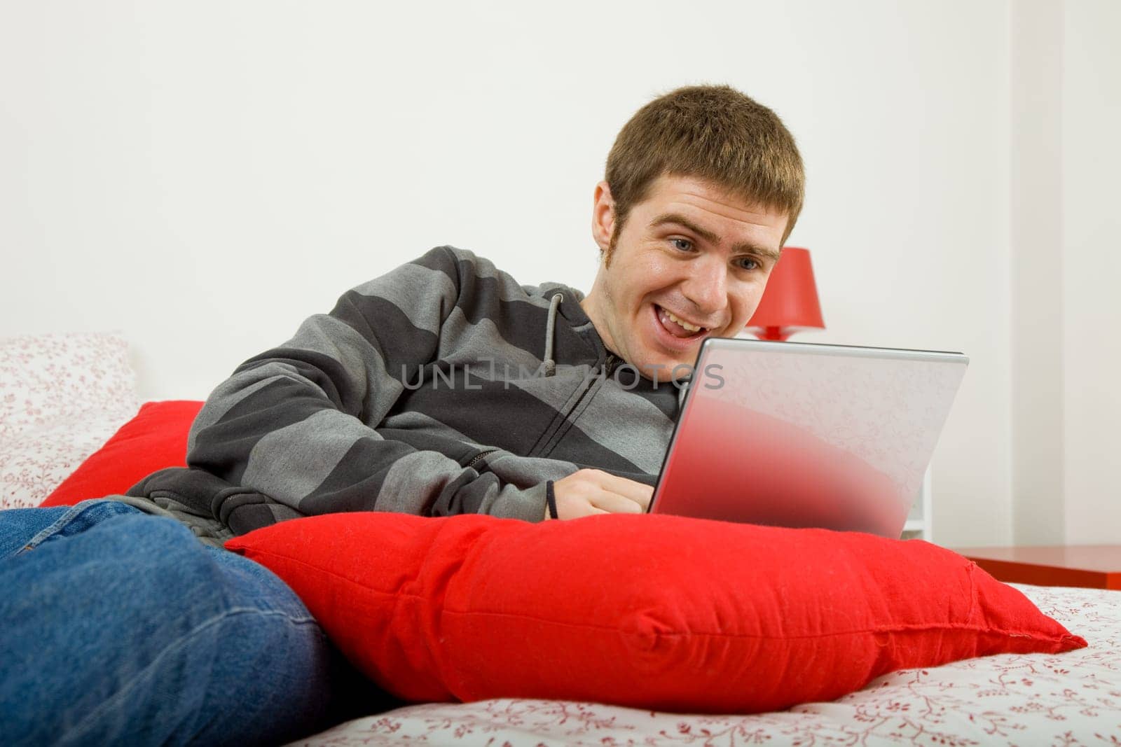 young casual man working with computer in bed
