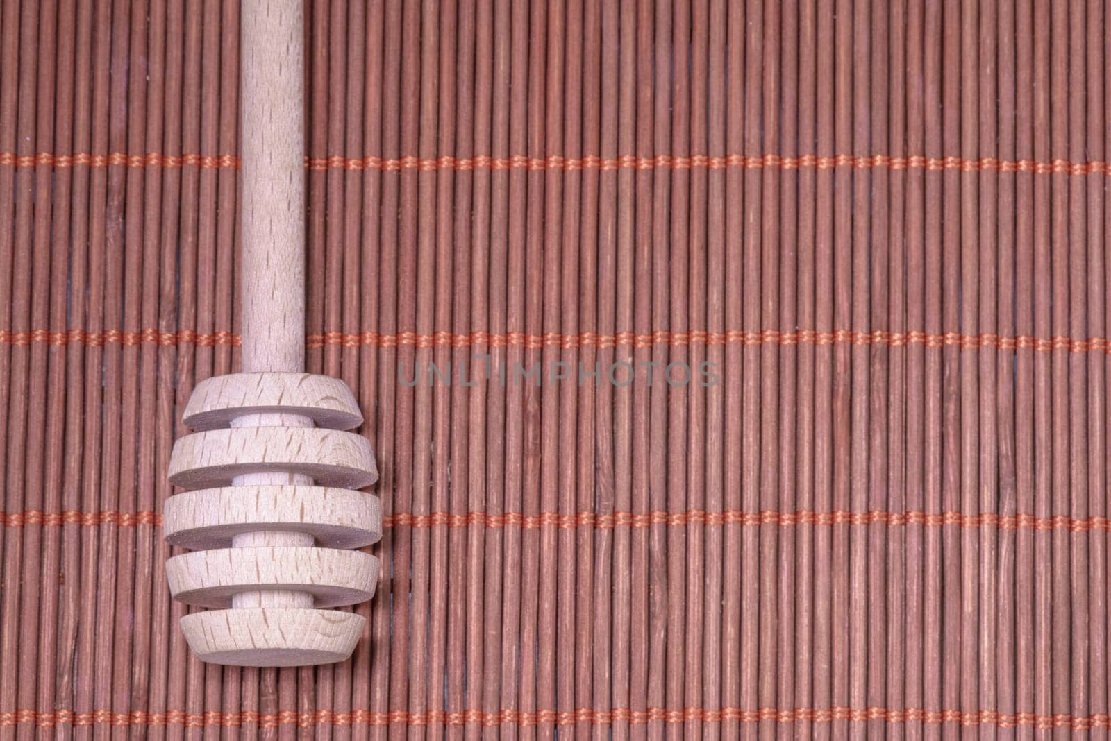 Wood Honey spoon on a nice wicker carpet as background