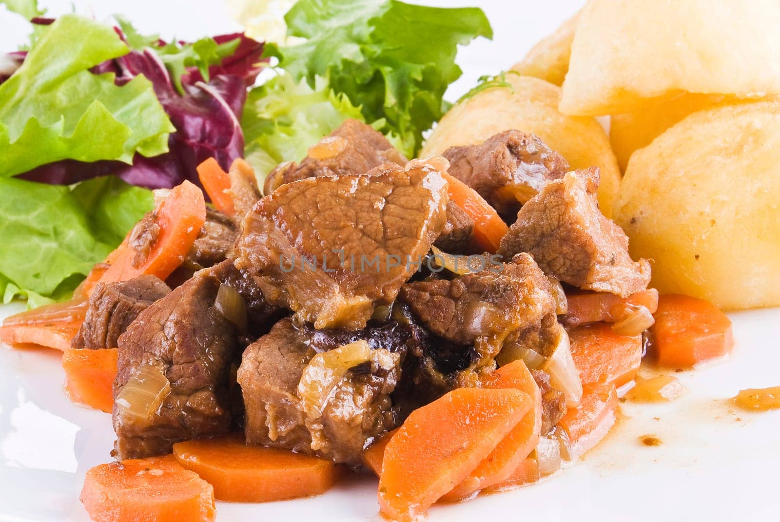 Meal of stewed beef steak with roast potatoes and fresh salad