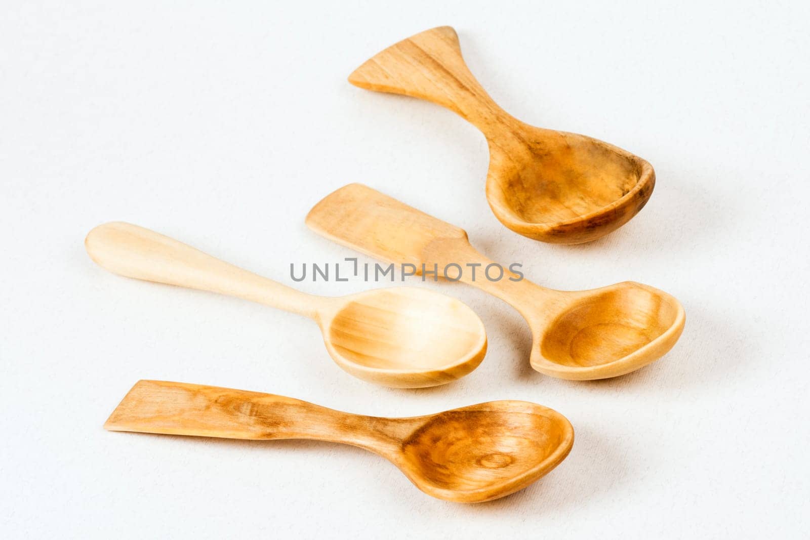 Four unique wooden spoons are on white background, wood carving concept.