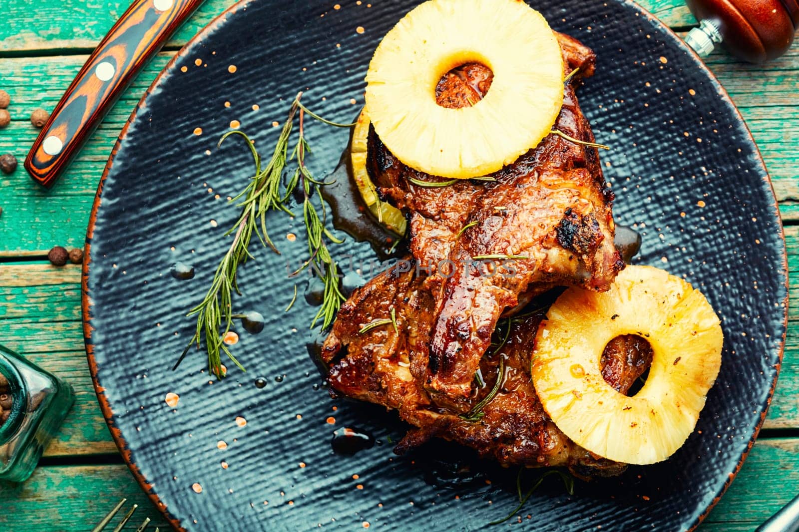 Tasty meat chop prepared with pineapple rings on old wooden table. Copy space