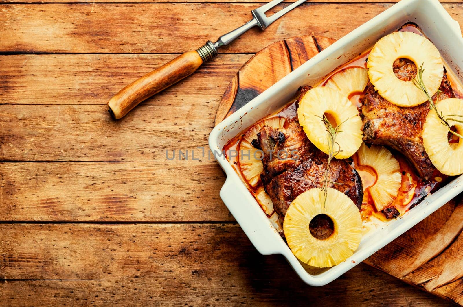 Tasty meat chop prepared with pineapple rings on old wooden table. Copy space