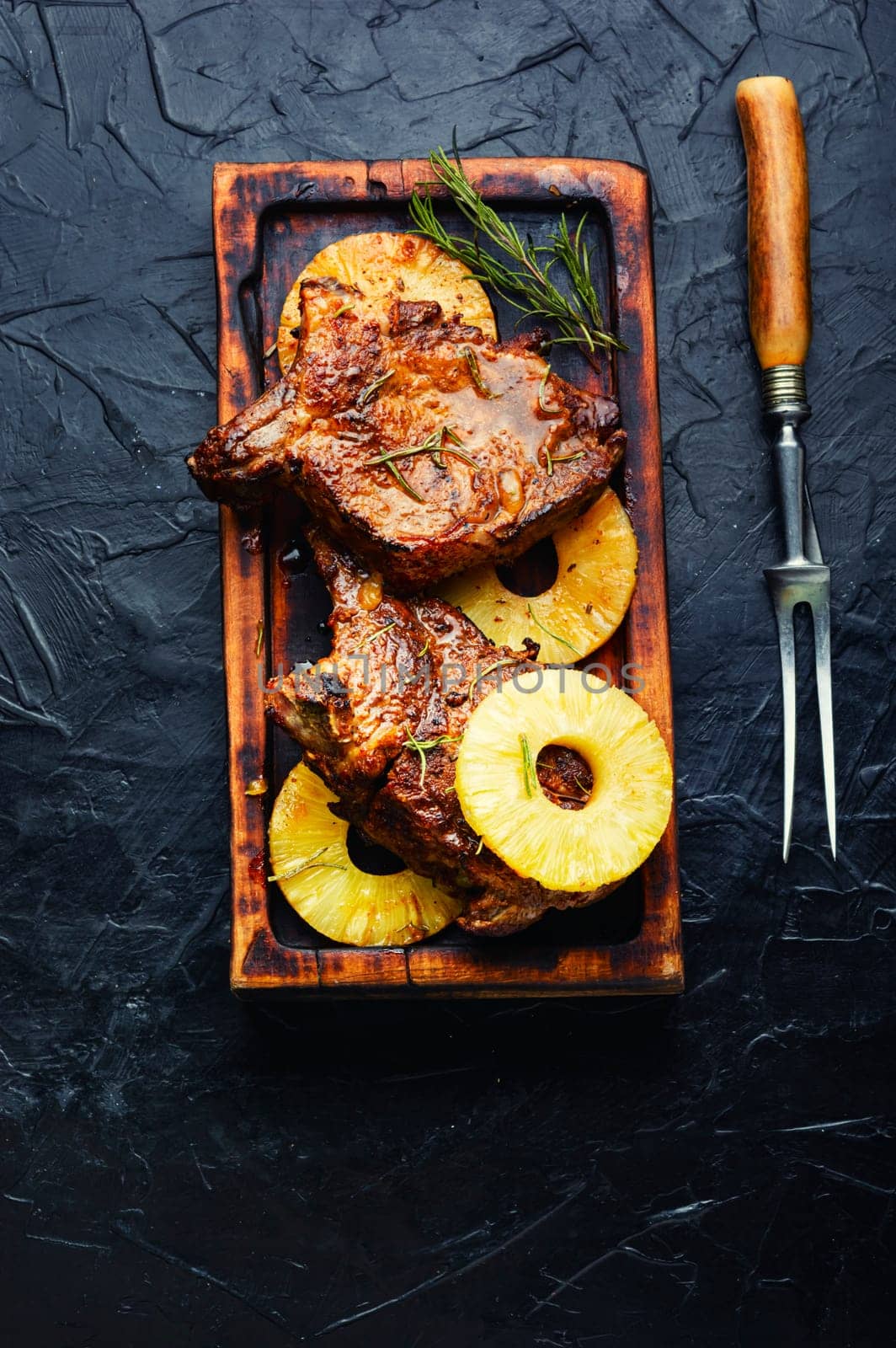 Tasty meat chop prepared with pineapple rings on old wooden table. Copy space