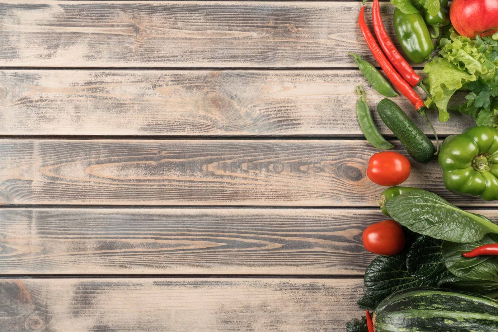 Green and red food mix layout of assortment of juicy organic garden vegetable on wooden background. Bell pepper, chili, tomato, cucumber and squash. Balanced meal banner. Copy space, top view, flatlay