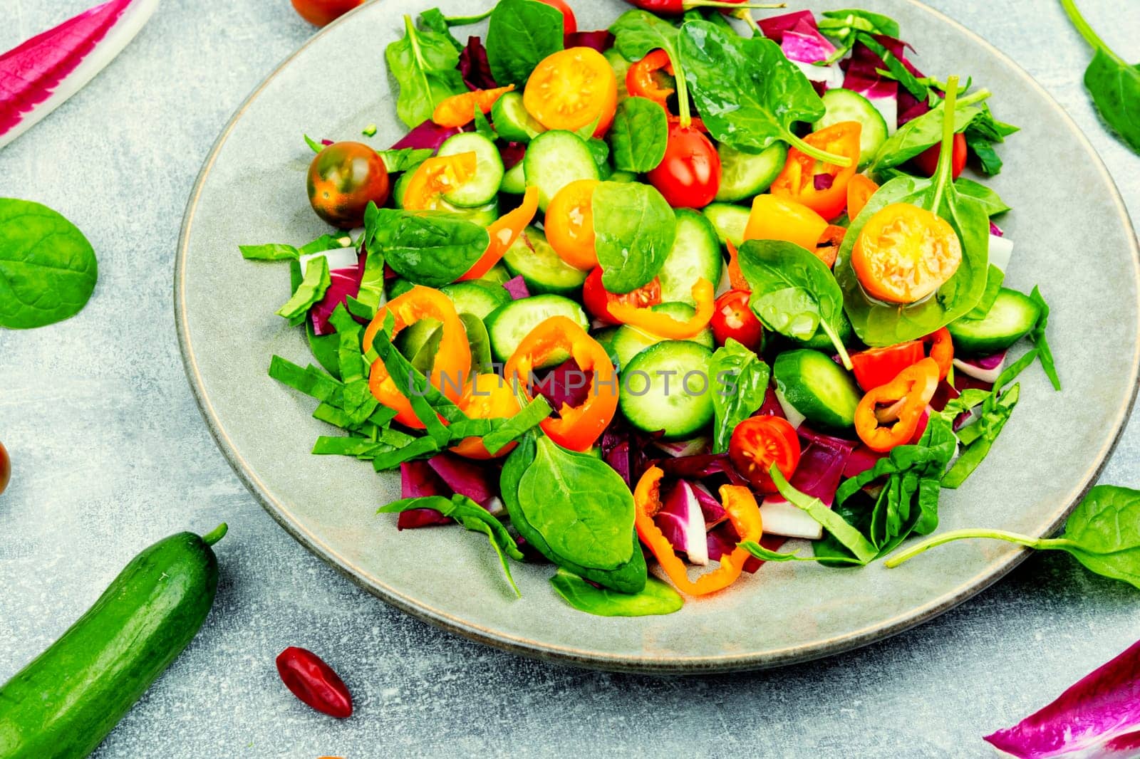 Summer delicious salad of tomatoes, cucumbers, peppers and spinach.