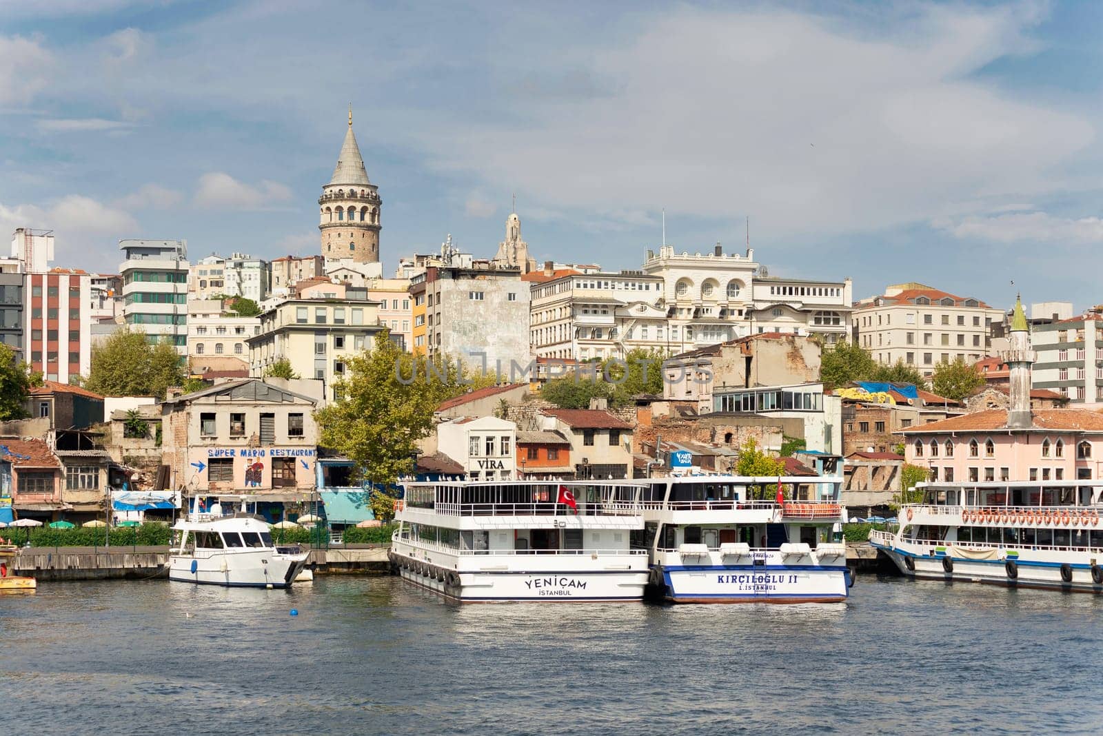 Istanbul city view from the sea of Golden Horn, with docked boats, and Galata Tower in the far end, in a summer sunny day