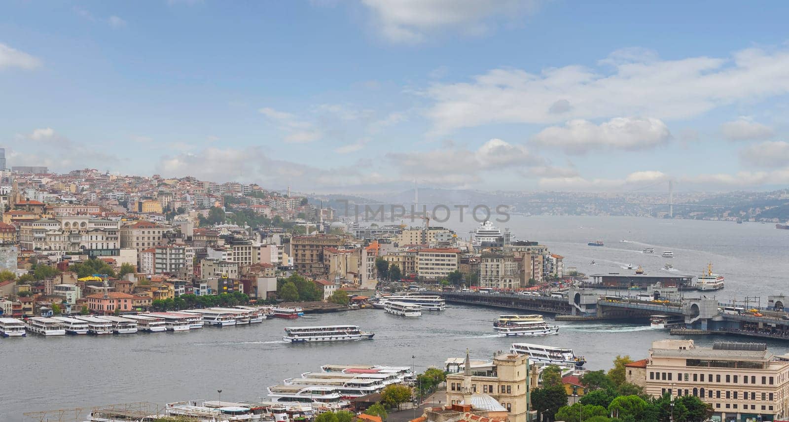 Aerial view of Golden Horn, with Galata Bridge and Karakoy Ferry Terminal with ferry boat approaching the terminal, and Bosphorus bridge in the far end, Istanbul, Turkey