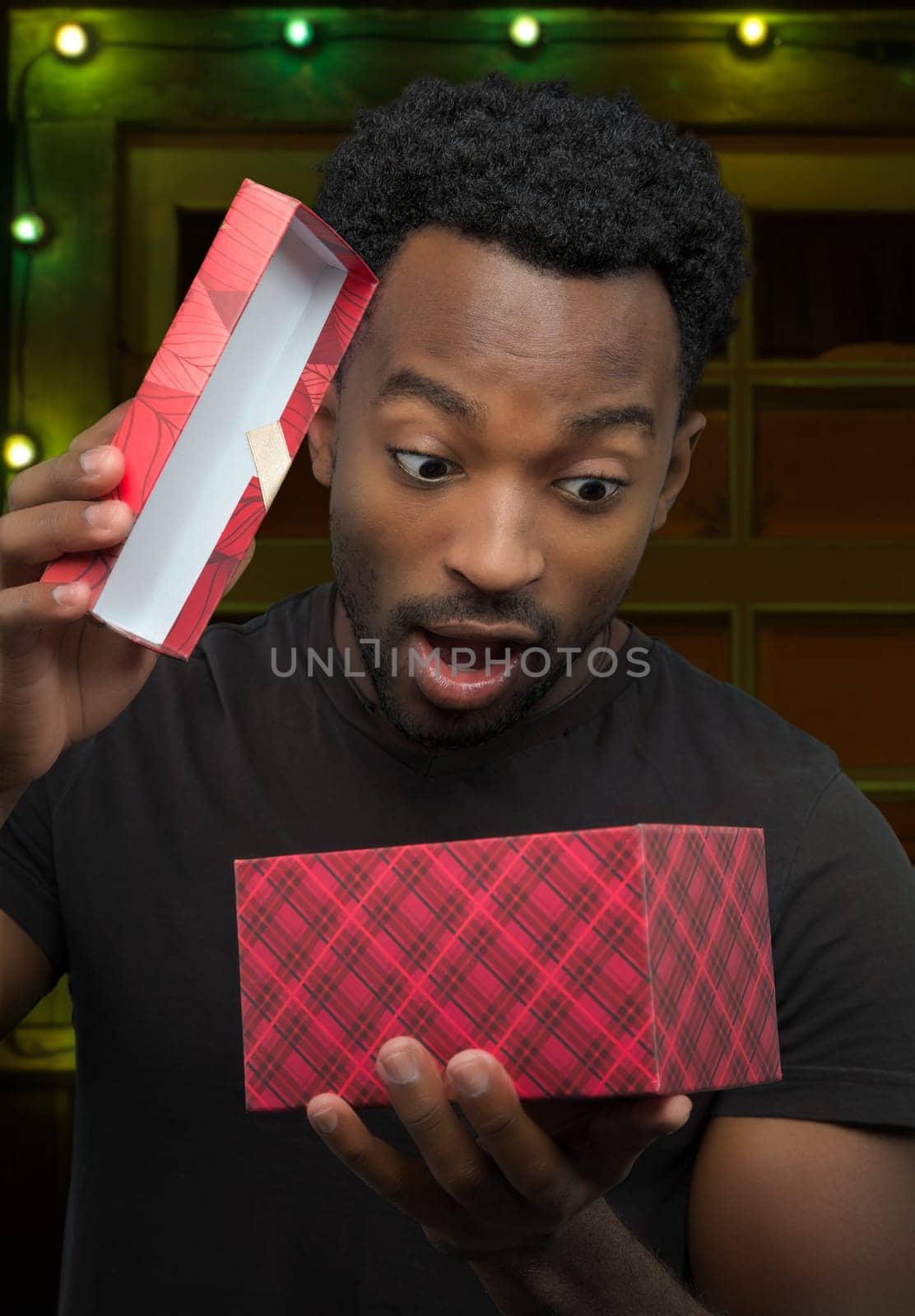 young man receiving a gift and opening box christmas night surprise holiday surprise decorated window