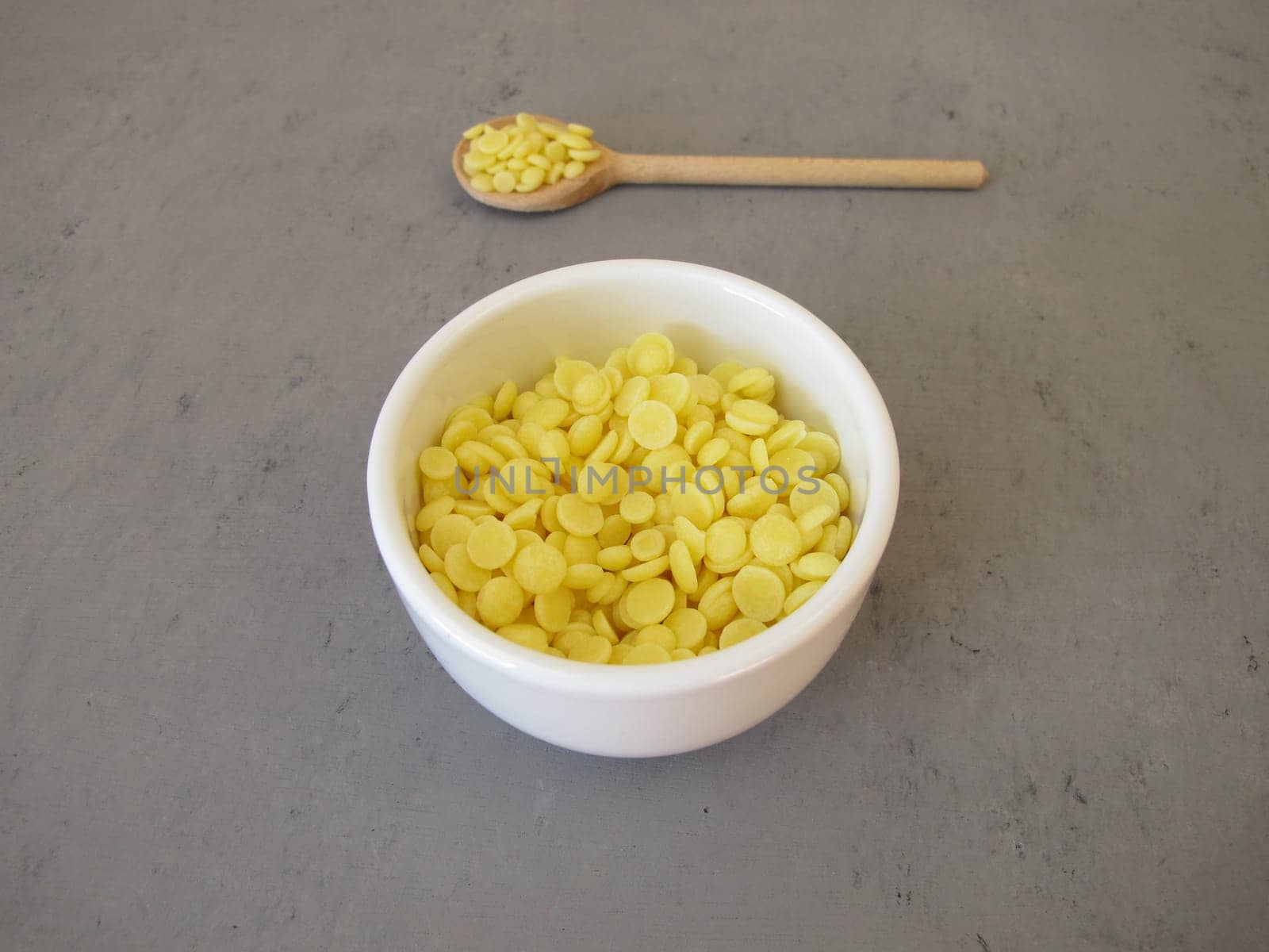 A bowl of light yellow cocoa butter chips as an ingredient for cooking and baking, chocolate making or personal care products