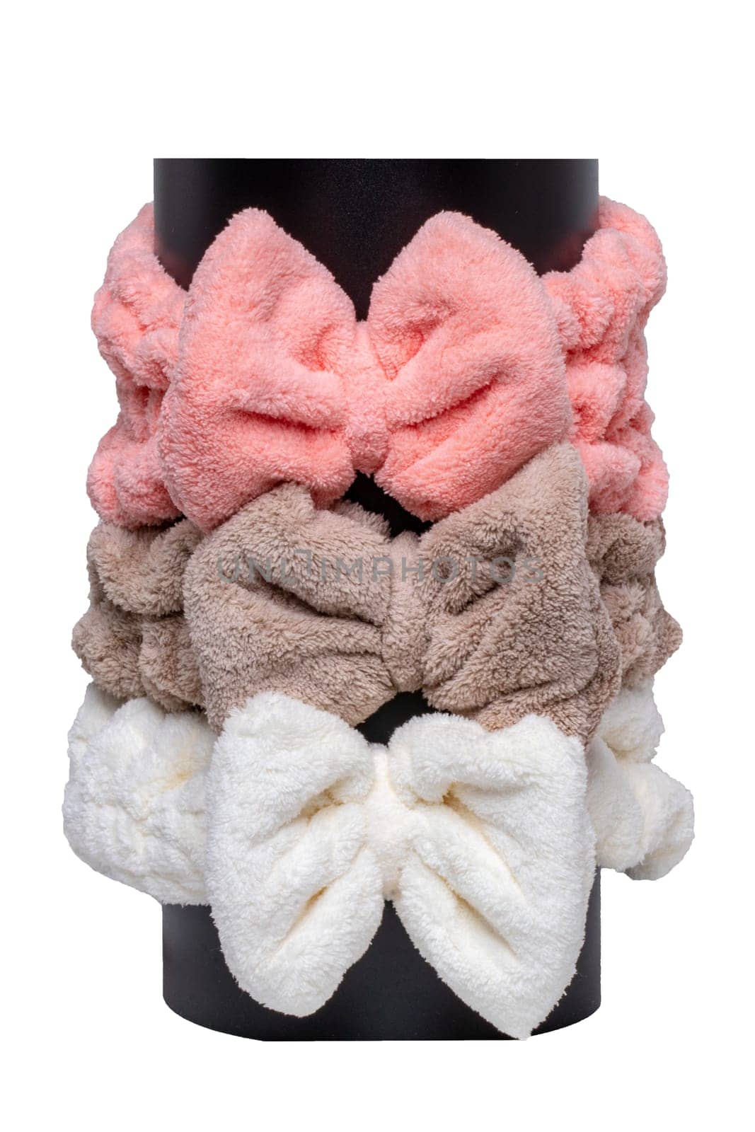 Three colorful hair bands on black pipe are made of high quality coral fleece which is super soft and skin friendly. Hairbands for face wash, make-up, shower, skin and beauty care for ladies and girls isolated.