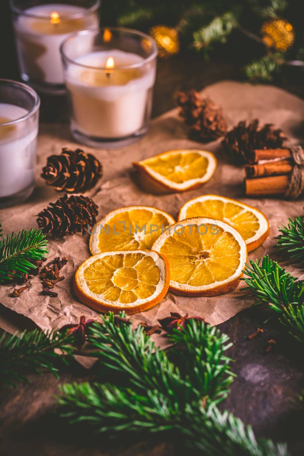 Dried orange and Christmas spices with branches of christmas tree, cinnamon, candles on kitchen table