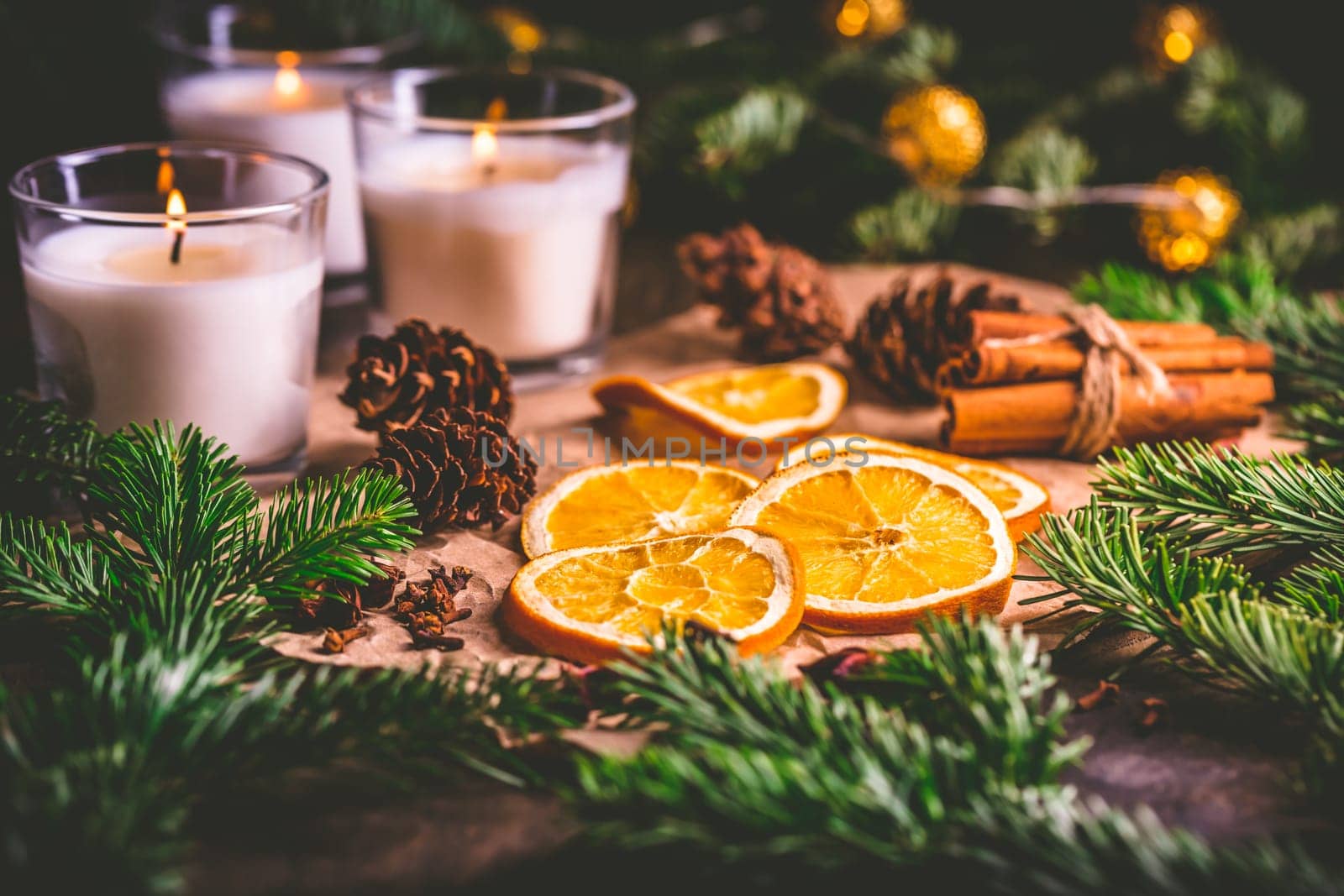 Dried orange and Christmas spices with branches of christmas tree, cinnamon, candles on kitchen table