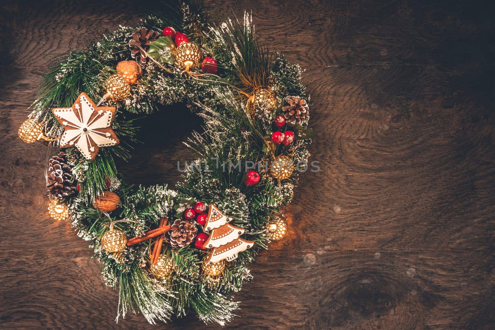 Christmas wreath decorated with ornaments and gingerbread on wooden background