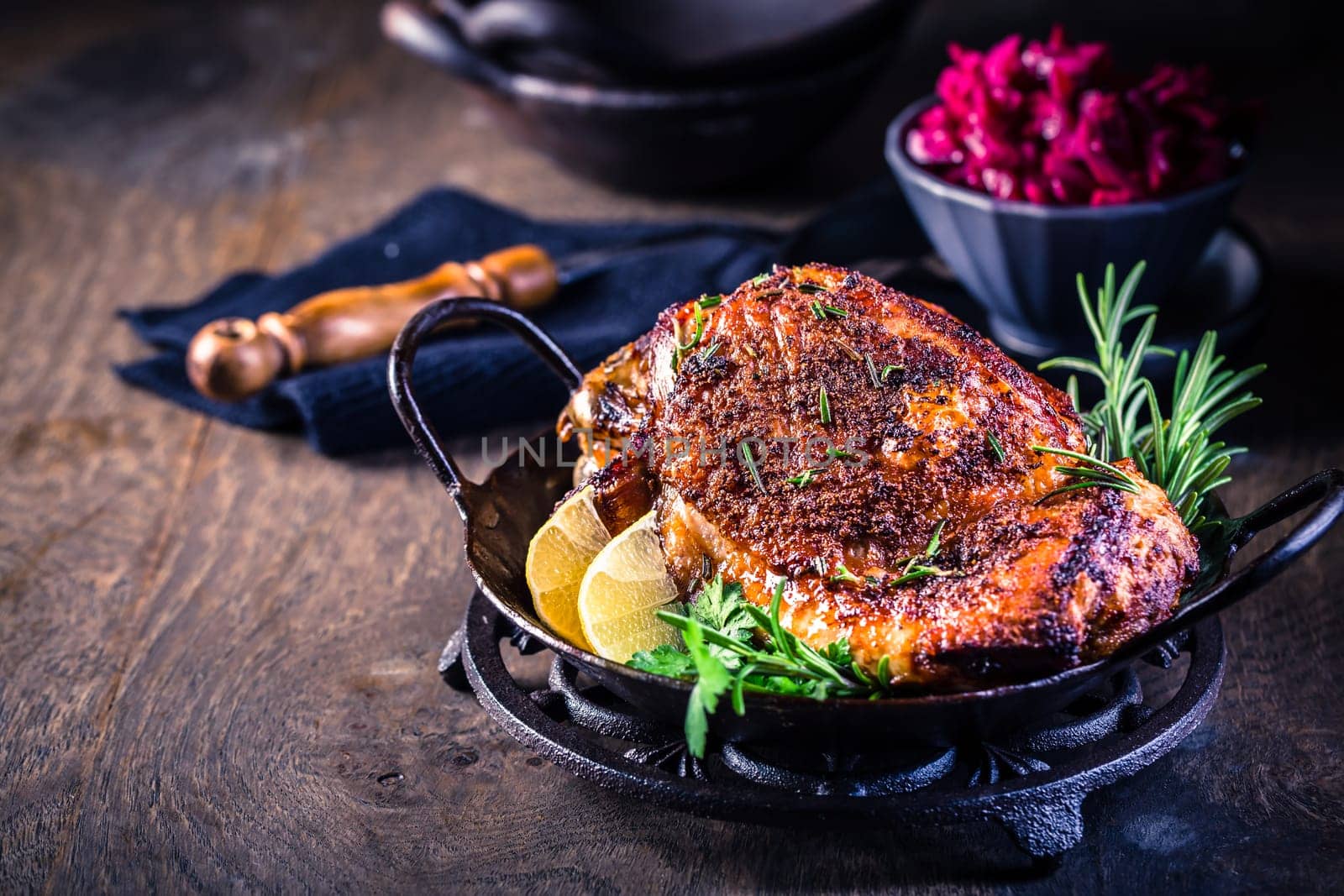 Roasted turkey knuckle with pickled red cabbage salad on wooden background