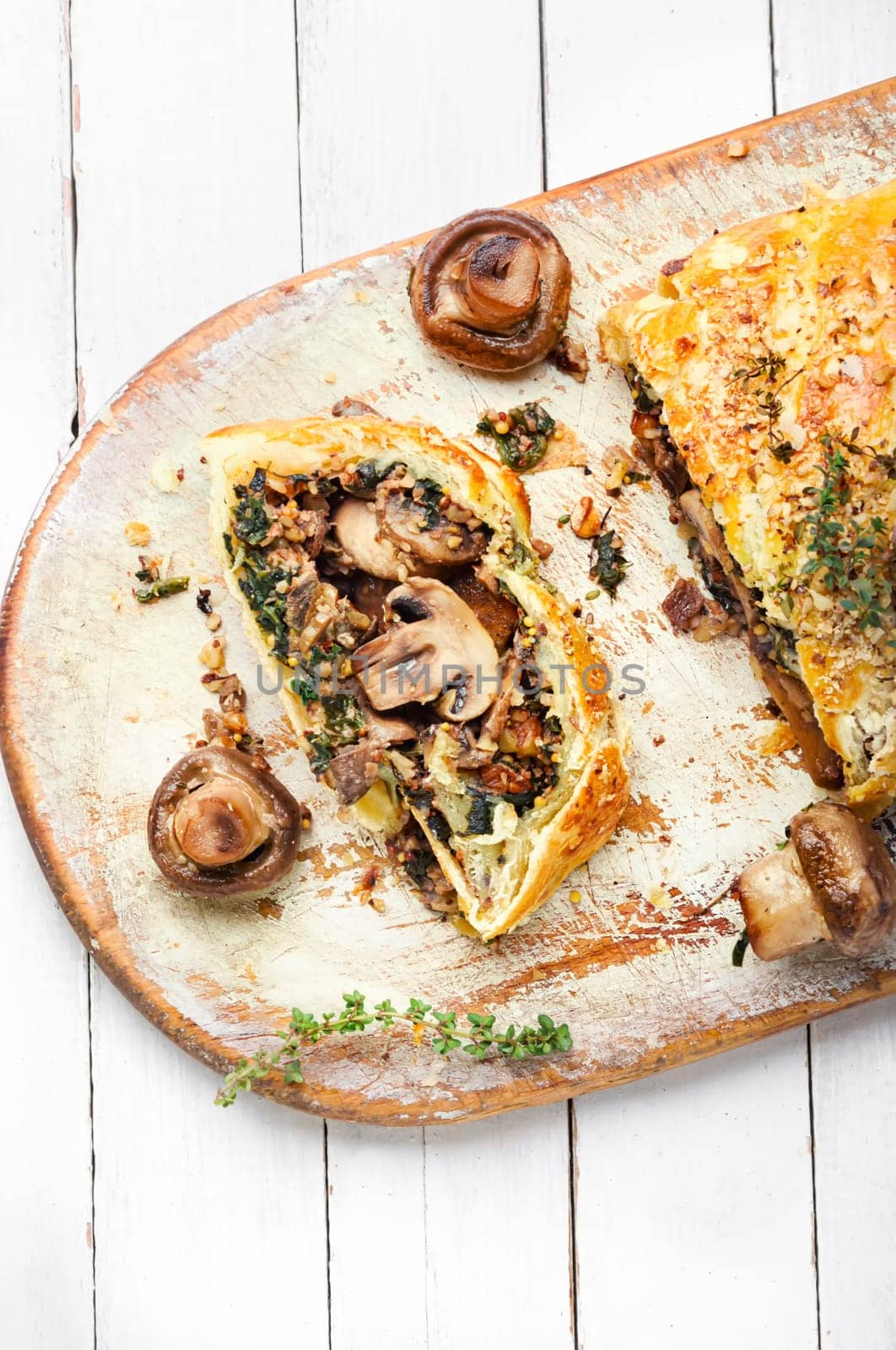Closed homemade mushroom pie. Sliced savoury mushroom champignons pie on old kitchen board