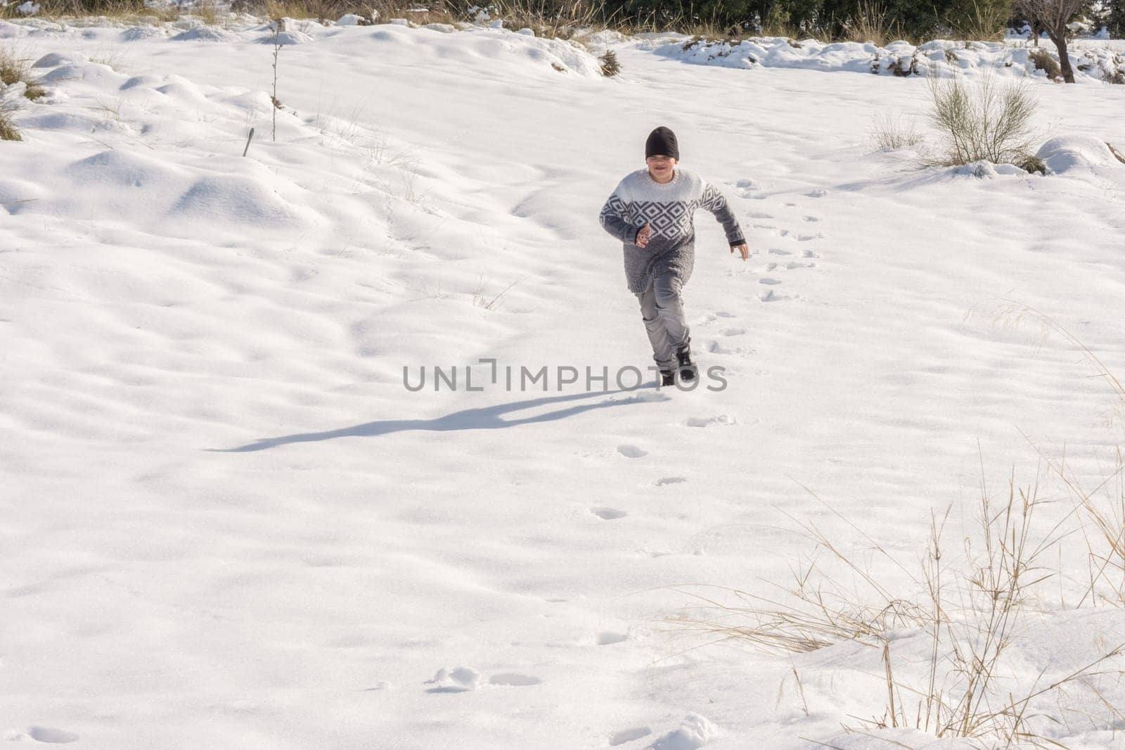 child running in the snow on a sunny day