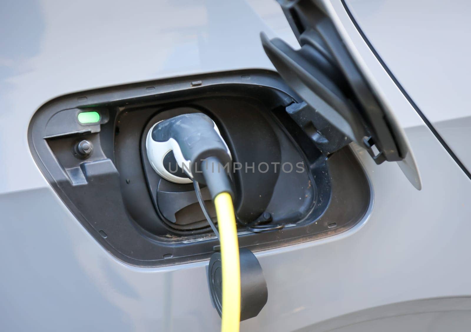 An electric car is charged at a charging station using a charging cable.