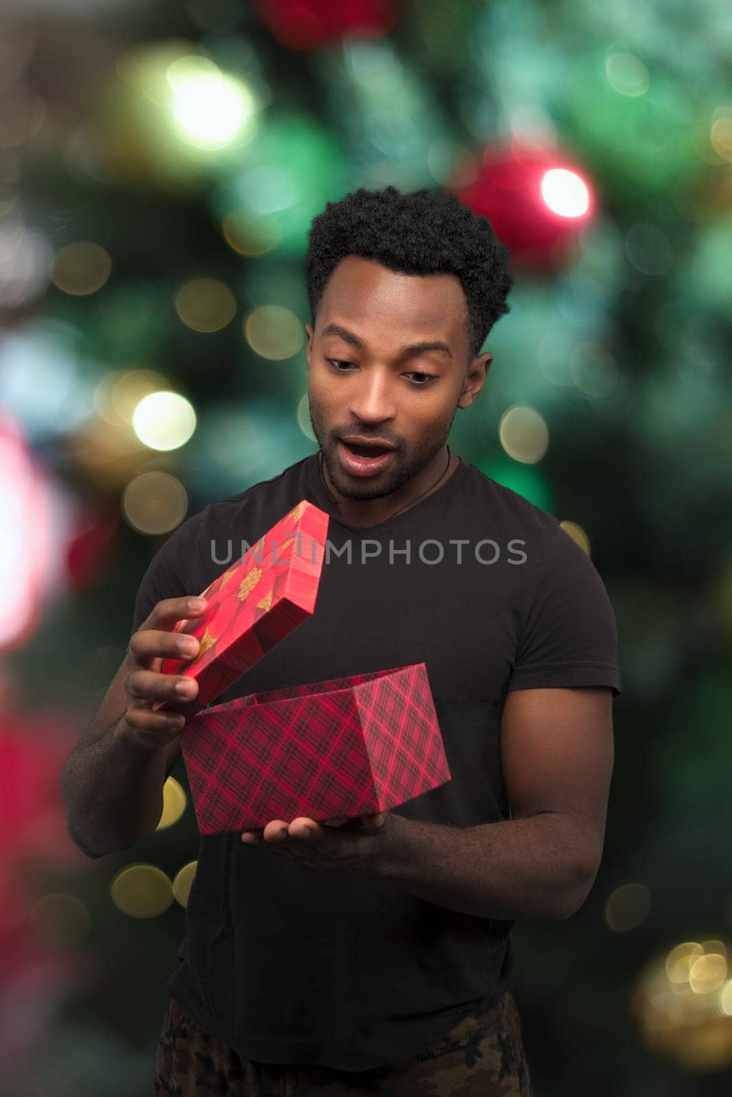 young man receiving a gift and opening box christmas night surprise holiday surprise decorations bokeh light