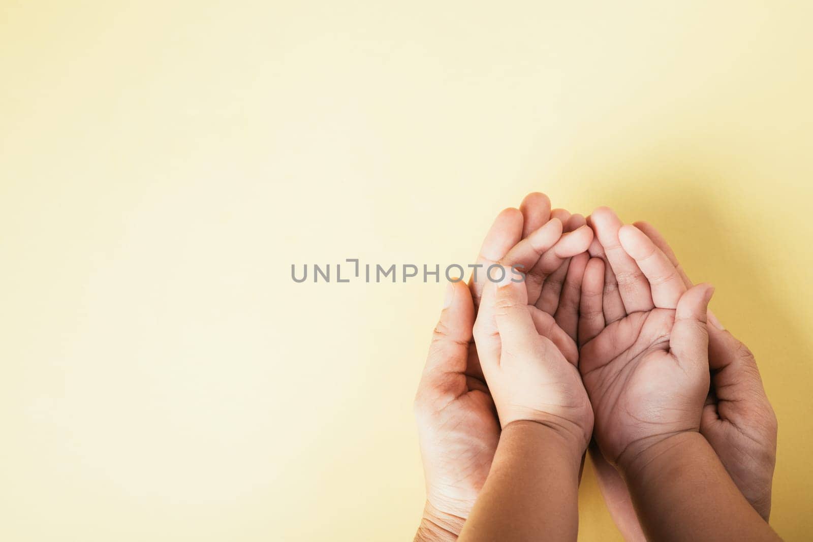 Closeup top view family hands stack palms studio shot isolated on yellow background, parents and kid holding empty free space on hand together, Gesture sign of support and love, Family and parents day