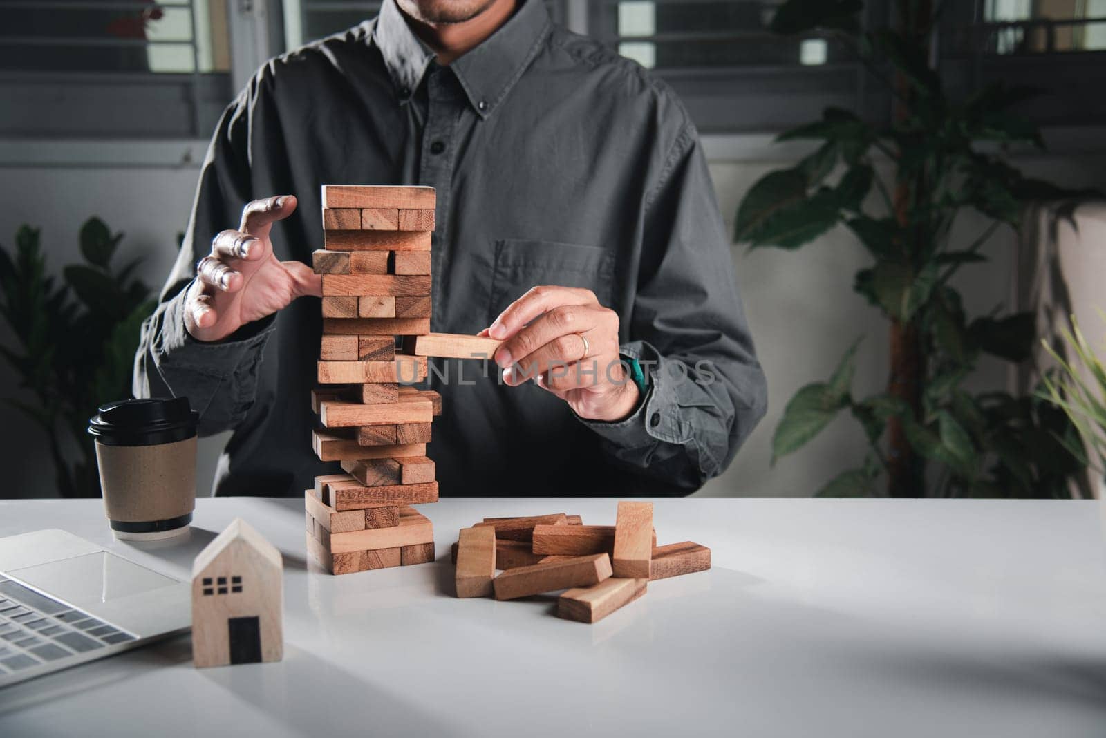 Alternative risk plan. Business hand playing tower wooden blocks game, man pull one wood block from tower he clenched his fist, show great joy in accomplishing it, Business gambling growth concept